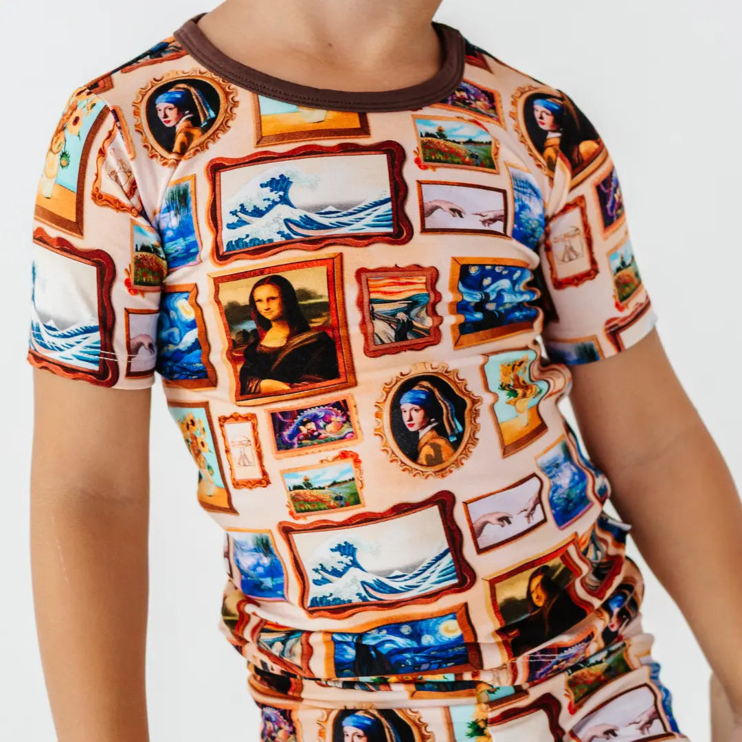 Close-up of a short-sleeve pajama top with a framed classic paintings print and brown collar.